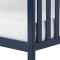 Close-up of white quilted mattress corner inside navy blue wooden bed frame showing mattress texture and slatted support