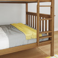 Close-up of solid wood bunk bed ladder and guardrail with gray knit blanket and yellow throw on mattress, natural wood finish