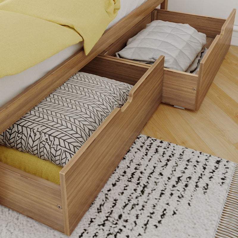 Wooden under-bed storage drawers open with folded blankets and patterned pillows, yellow bedding and textured rug on hardwood floor