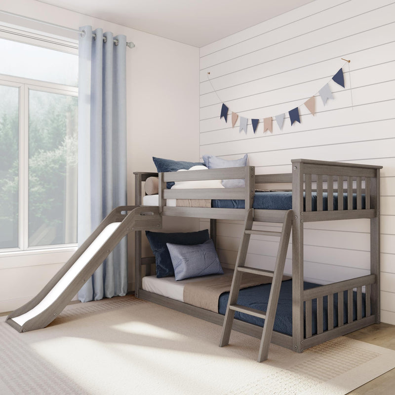 Gray wooden bunk bed with slide in a children's room, navy and beige pennant garland on white shiplap wall, light blue curtains and pillows