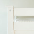 Close-up of white wooden bunk bed frame corner with visible screw and mattress edge, modern minimalist bedroom furniture detail
