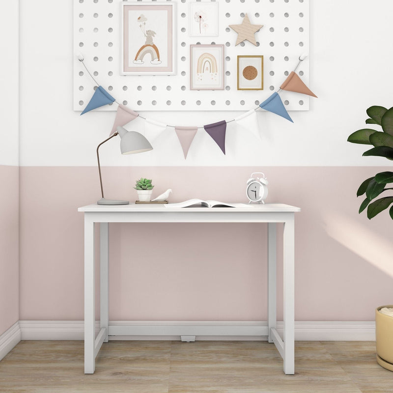 White desk in pastel pink kids' room with bunting and framed rainbow art, desk lamp, succulent, alarm clock and potted plant