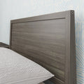 Close-up of modern gray wood headboard with textured white bedding and light-blue patterned wallpaper in contemporary bedroom