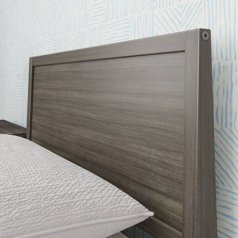 Close-up of modern gray wood headboard with textured white bedding and light-blue patterned wallpaper in contemporary bedroom