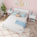 Pastel pink kids bedroom with white bed, blue and blush pillows, rainbow wall art, bedside tables with lamps and herringbone wood floor