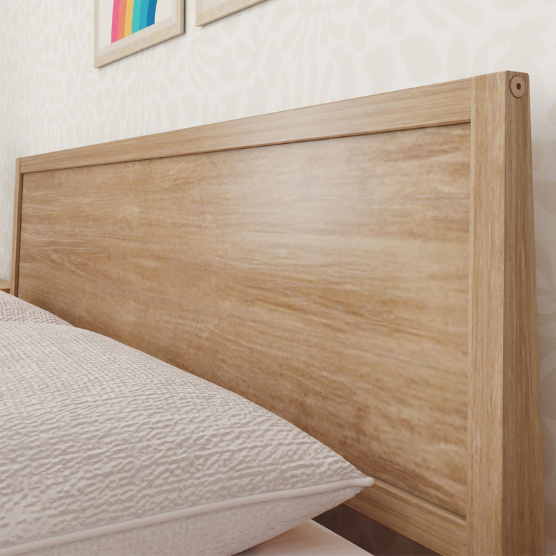 Close-up of a light oak wooden headboard with visible wood grain, white quilted mattress and subtle patterned beige wallpaper in a modern bedroom interior