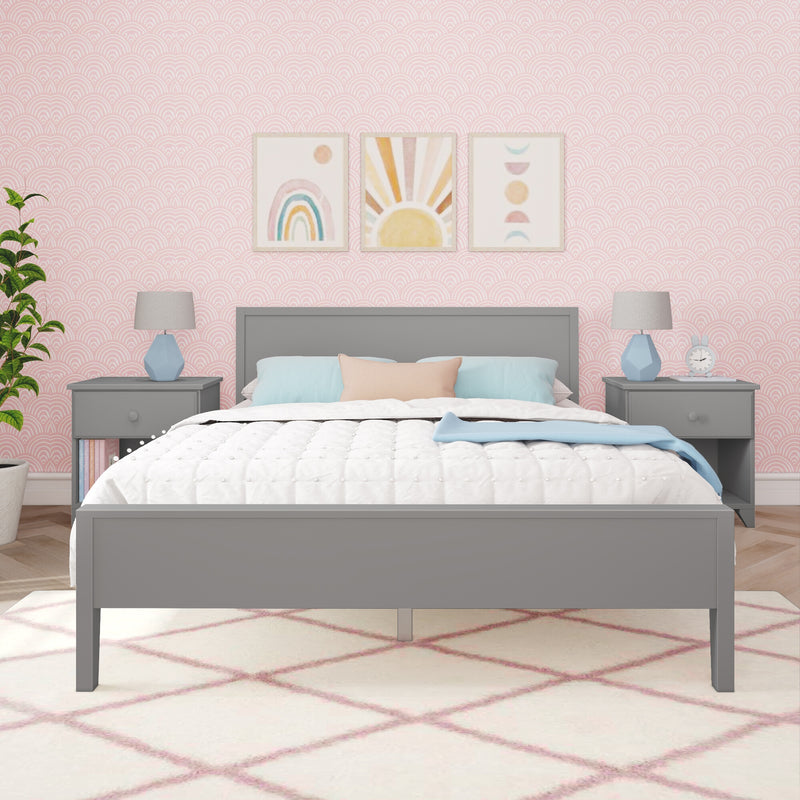 Girl's pastel bedroom interior with grey bedframe, white quilted bedding, pink scalloped wallpaper, three rainbow and sun prints above headboard, matching nightstands with blue lamps and nursery decor