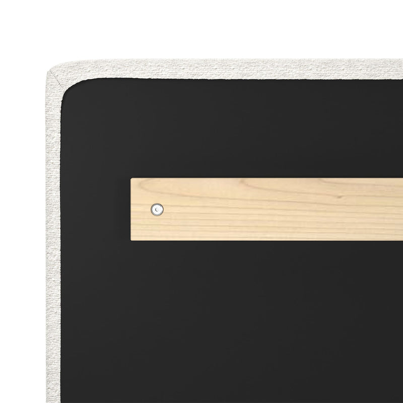Close-up of upholstered headboard corner with white textured fabric trim, black backing and a wooden mounting plate secured by a screw