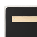 Close-up of an upholstered headboard corner showing white boucle fabric trim, black fabric panel and light wood mounting bracket with a visible screw
