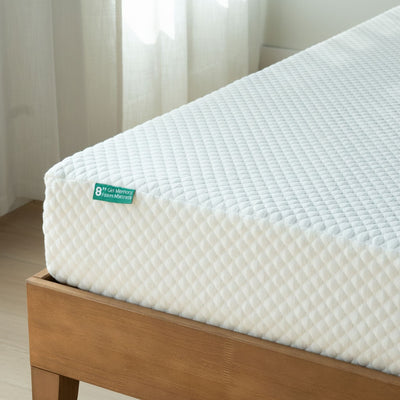 8-inch gel memory foam mattress with white quilted breathable cover on a wooden bed frame in a bright minimalist bedroom