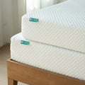Close-up of two stacked 8-inch white quilted gel memory foam mattresses on a wooden bed frame in a bright minimalist bedroom