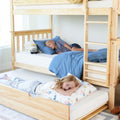 Children sleeping on a wooden bunk bed with trundle and twin mattresses, blue bedding and playful pillow in a bright kids' bedroom