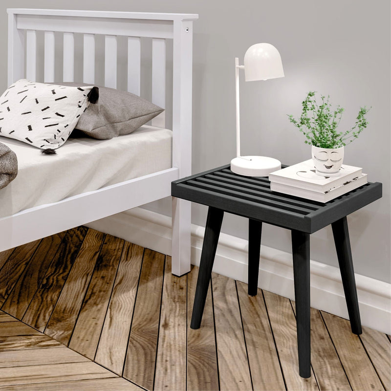 Modern bedroom with white bed, stylish black side table, and contemporary table lamp on wooden floor for cozy interior design.