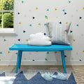 Bright blue bench with cloud pillow and gray cushion in a modern living room with triangle pattern wallpaper and cozy slippers on a geometric rug.