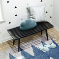 Cozy modern entryway with black bench, decorative pillows, patterned rug, and cute slippers.
