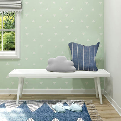 Mint green nursery with white triangle wallpaper, white slatted bench topped with a gray cloud pillow and blue striped cushion, window with gray roman shade and blue patterned rug
