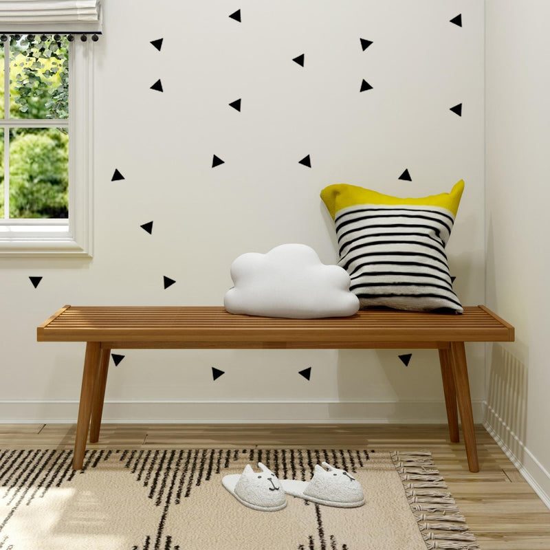 Cozy toddler room with playful cloud pillow and striped cushion on wooden bench, accented by cat slippers and geometric wall design.