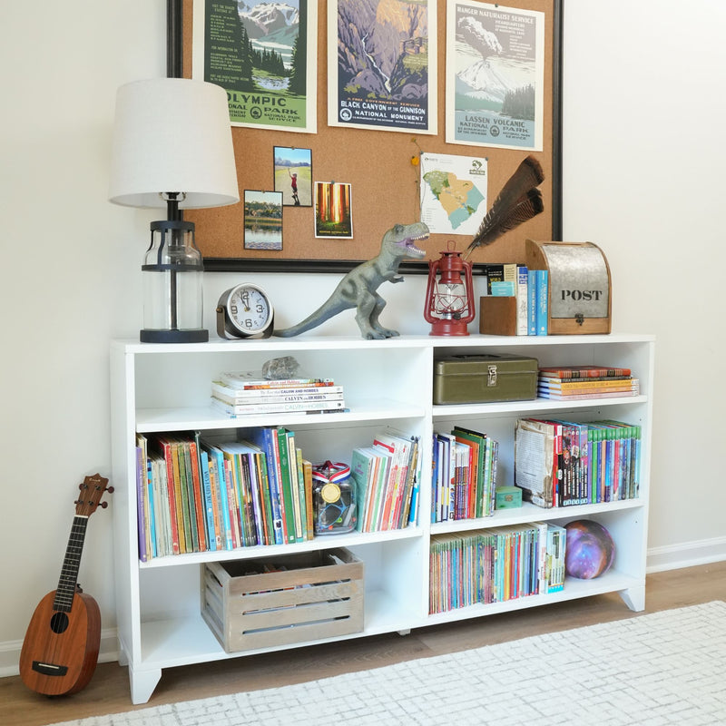 Kids bookshelf and playroom storage with colorful children's books, toy dinosaur, lamp and clock, red lantern, ukulele and corkboard with national park posters