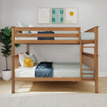 Wooden twin bunk bed in modern coastal children's bedroom with neutral bedding, navy throw, sun plush pillow, potted plant and three framed ocean-themed prints