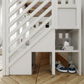 White wooden loft bunk bed with diagonal slat railing and built-in storage cubbies, stacked books and navy sneakers on hardwood floor, modern kids' bedroom furniture