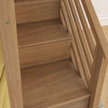 Close-up of oak hardwood staircase treads and vertical slatted railing showing natural wood grain in a modern interior