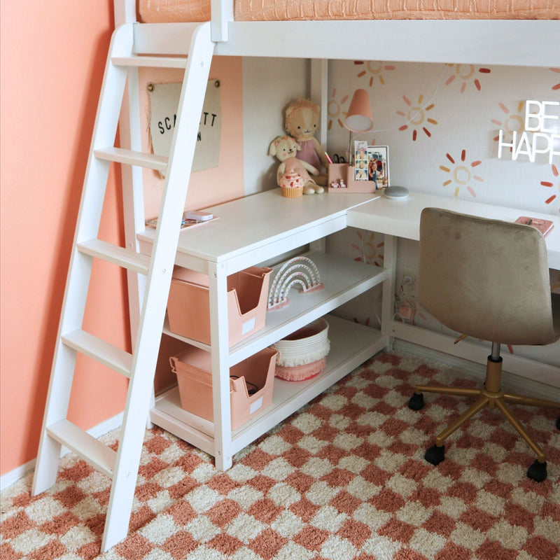 Peach and white kids loft bed with ladder and built-in desk, pink storage bins, plush toys and study nook in modern children's bedroom