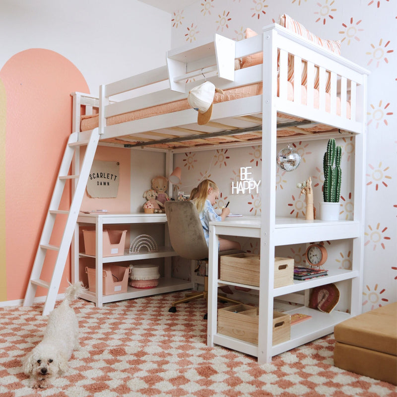 Kids loft bed with built-in desk in peach and white girls' bedroom, child studying with plush toys, cactus, disco ball and small dog on patterned rug