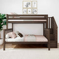 Modern dark wood twin-over-full bunk bed with built-in stairs, blush pink bedding and pillows, animal framed wall art, indoor plant and textured white rug in a kids' bedroom