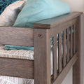 Close-up of a modern gray wooden crib rail with teal pillow and gray patterned bedding in a neutral nursery