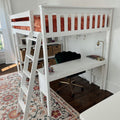 White loft bed with built-in desk and ladder, orange faux-fur bedding, green velvet swivel chair, woven storage baskets and patterned rug in a bright home office/bedroom nook