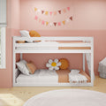 White bunk bed in a pink kids' bedroom with pastel flag bunting, daisy cushion, orange pillows and wooden floor, modern nursery decor