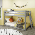 Gray wooden bunk bed in a modern children's bedroom with yellow bedding, decorative tassel garland, lion throw pillow, polka-dot rug and ladder on light wood floor