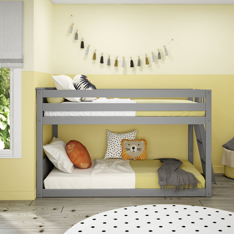 Gray bunk bed with yellow bedding in a modern children's bedroom featuring tassel garland wall decor, lion and polka-dot pillows, roman shade and wood flooring.