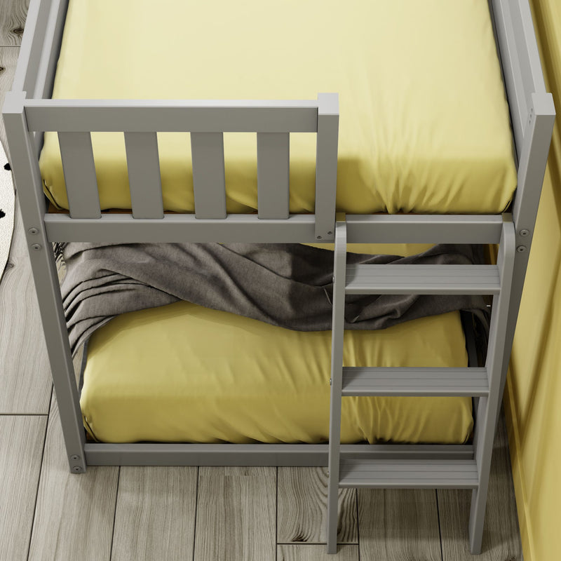 Top-down view of white bunk bed frame and ladder with yellow bedding, gray blanket and light wood plank flooring