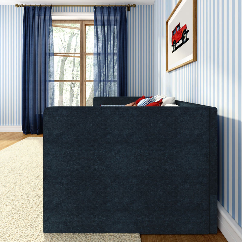 Cozy modern living room corner with navy blue sofa and red accent pillows, light-blue striped wallpaper, sheer navy curtains over a wooden window, framed red toy car wall art, beige rug and hardwood floor, natural light, stylish home decor interior
