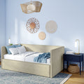 Cozy modern bedroom with beige upholstered daybed, light blue walls, woven rattan wall art, navy nightstand, gold lamp, and textured blue rug