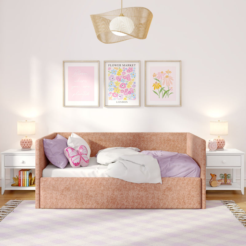 Cozy pink girls' bedroom interior with peach upholstered daybed, butterfly throw pillow, lilac bedding, framed floral wall art, woven rattan pendant light and matching bedside lamps, stylish kids' room decor