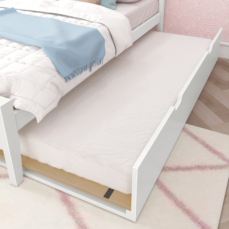 White twin trundle bed with pull-out mattress, pink scallop wallpaper and pastel bedding topped by a blue throw in girls' bedroom