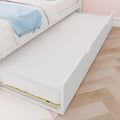 White kids trundle bed with pull-out mattress, blue throw blanket, pink patterned wallpaper and hardwood floor