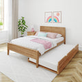Scandinavian bedroom with wooden platform bed and pull-out trundle, pastel pink and mint bedding, rainbow wall art, bedside lamp and indoor plant