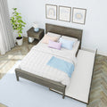 Modern bedroom with dark wooden bed frame and pull-out trundle, white quilted bedding and pastel pillows, wooden nightstand with blue lamp, potted plant, framed wall art and herringbone hardwood floor