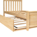 Natural pine wood platform bed frame with vertical slatted headboard and pull-out trundle on slatted base, light unfinished wood grain