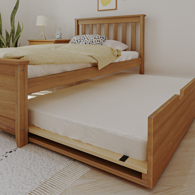 Natural wood trundle bed with pull-out mattress in minimalist bedroom, yellow throw blanket, patterned pillow, bedside lamp and alarm clock