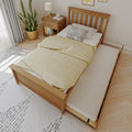Wooden trundle bed with yellow duvet in a Scandinavian-style bedroom, slatted headboard, pull-out mattress, wooden nightstand, potted snake plant and speckled throw pillow