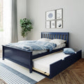 Navy blue wooden trundle bed with blue striped bedding in a modern kids' bedroom with sports-themed wall art, potted plant and gray curtains