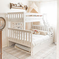 White wooden bunk bed with ladder and canopy in a neutral boho nursery, cozy bedding, stuffed toys and botanical wall art