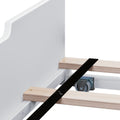 Close-up of platform bed frame showing wooden slats, metal center support bracket and caster wheel on white bed base