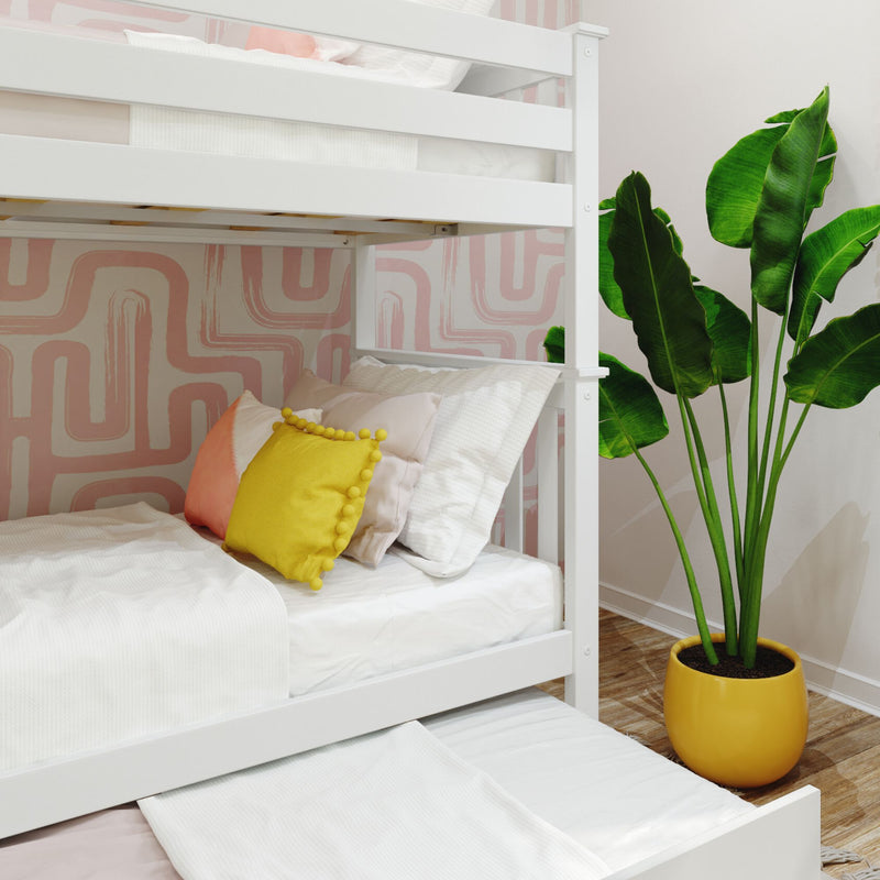 White wooden bunk bed with pull-out trundle, crisp white bedding and yellow pom-pom pillow against pink geometric wallpaper and potted banana-leaf plant — modern kids' bedroom decor