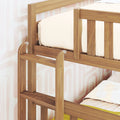 Close-up of a solid wood children's bunk bed showing a sturdy safety guardrail, slatted frame and cream bedding with a natural wood finish