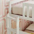 White wooden bunk bed guardrail and ladder with beige bedding against pink retro patterned wallpaper, children's bedroom nursery decor